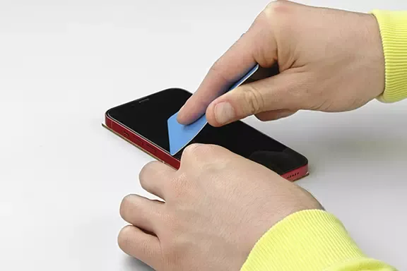 Panzerglas wird mit einer Kreditkarte blasenfrei auf dem Handy-Display angebracht